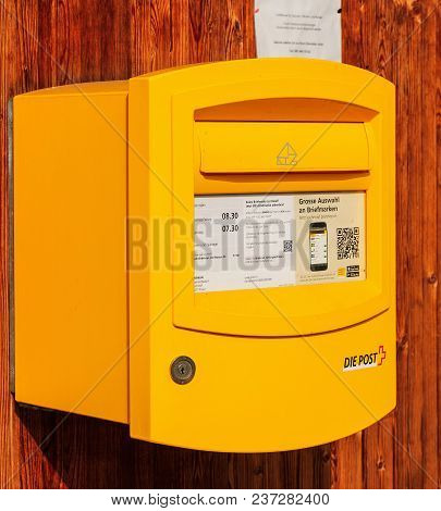 Filisur, Switzerland - 3 March, 2017: A Yellow Mail Box Of Swiss Post On A Wooden Wall, Main Focus O