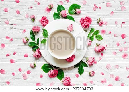 Flowers Composition. Frame Made Of Fresh Rose Flowers With Cup Of Cappuccino On White Wooden Backgro