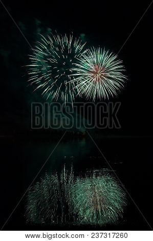 Fireworks Of Many Colors On  Display And Refelcting In A Lake