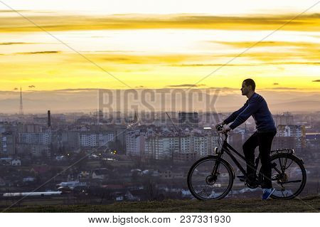 Dark Silhouette Of Man Standing Near A Sports Bicycle With The Night City View Behind. Active Life A