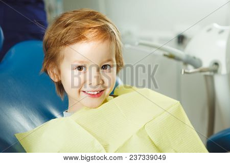Little Boy Sits On Dentist's Chair In Good Mood After Dental Procedures. Young Patient With Healthy 