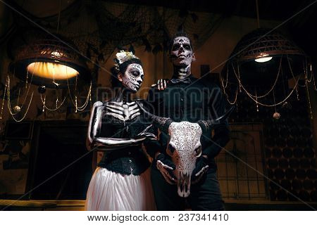 Portrait of a dead couple. Skeleton coming from a cupboard and woman with flower 
