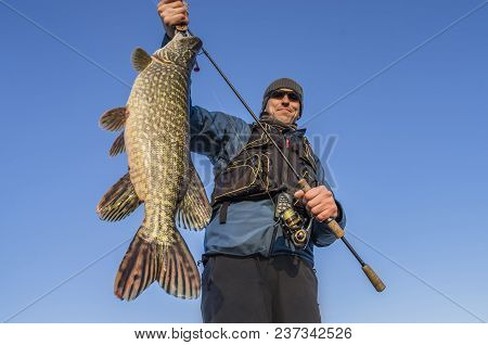 Happy Fisherman Holding Big Pike Fish Trophy And Fishing Rod