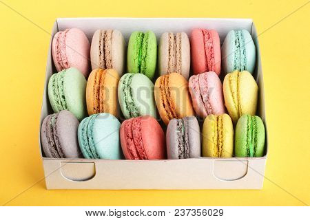 Colorful Macarons In Box On Yellow White Background Closeup.