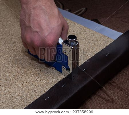 Workman Using Staples And Stapler To Upholster Paricle Board. Diy