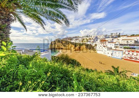 Sandy Beach Surrounded By Cliffs With Palm Trees In Carvoeiro, Algarve, Portugal