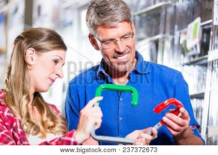 Young woman asking shop assistant in ironware department of hardware store about mountings for window boxes