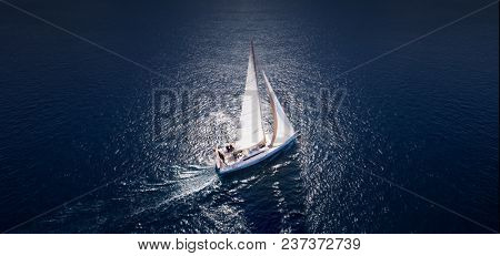 Sailing ship yachts with white sails at opened sea. Aerial - drone view to sailboat in windy condition.