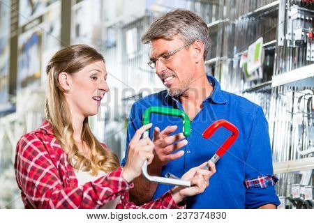Young woman asking shop assistant in ironware department of hardware store about mountings for window boxes