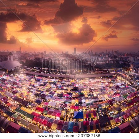 Ratchada Train Night Market With Street Food And Clothes During Cloudy Sunset With Sunbeams In Bangk