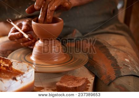 Close-up Hands Of A Male Potter In Plaid Shirt And Dirty Apron Who Molds A Vase From Clay, Selective