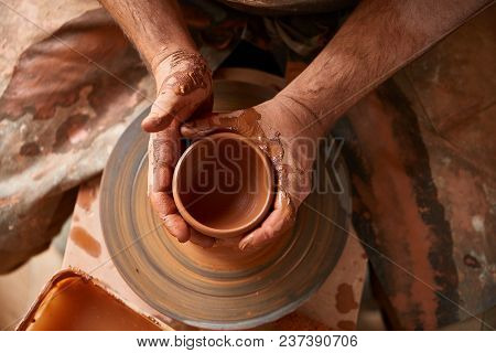 Close-up Hands Of A Male Potter In Plaid Shirt And Dirty Apron Who Molds A Vase From Clay, Selective