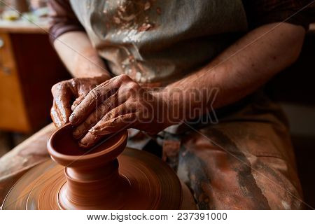 Close-up Hands Of A Male Potter In Plaid Shirt And Dirty Apron Who Molds A Vase From Clay, Selective