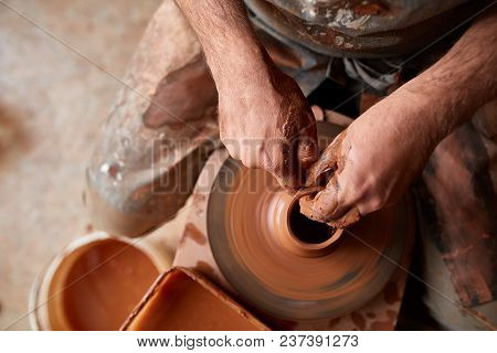 Close-up Hands Of A Male Potter In Plaid Shirt And Dirty Apron Who Molds A Vase From Clay, Selective