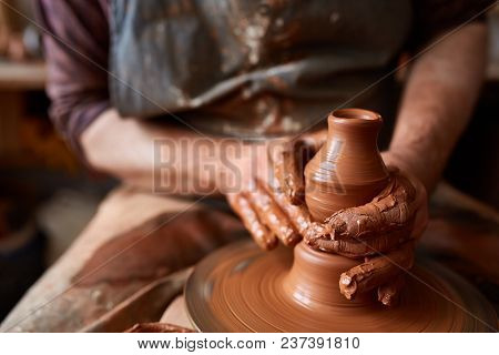 Close-up Hands Of A Male Potter In Plaid Shirt And Dirty Apron Who Molds A Vase From Clay, Selective