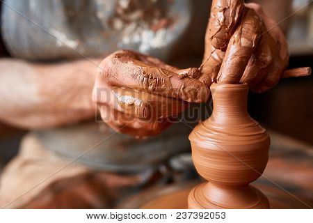 Close-up Hands Of A Male Potter In Plaid Shirt And Dirty Apron Who Molds A Vase From Clay, Selective
