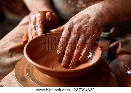 Close-up Hands Of A Male Potter In Plaid Shirt And Dirty Apron Who Molds A Vase From Clay, Selective