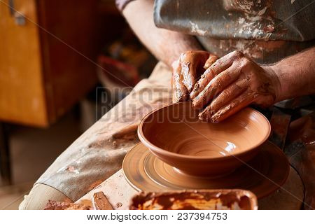 Close-up Hands Of A Male Potter In Plaid Shirt And Dirty Apron Who Molds A Vase From Clay, Selective
