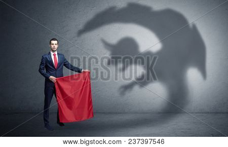 Businessman standing with red cloth in his hand and imp shadow on the background