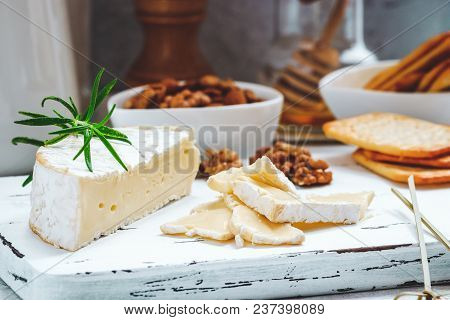 Cheese Plate Served With Crackers, Honey And Nuts. Camembert On White Wood Serving Board Over White 