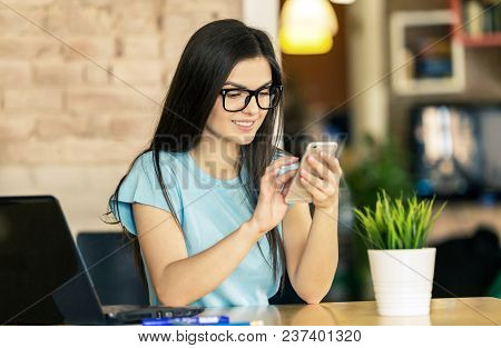 Dark Hair Student Girl Wears Blue Shirt And Eyeglasses Using Smartphone For Text Messages In Modern 