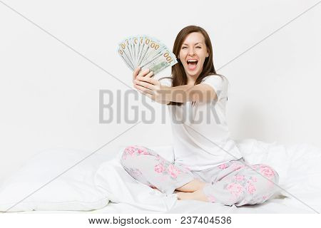 Young Fun Happy Woman Sitting In Bed With White Sheet, Pillow, Wrapping In Blanket On White Backgrou