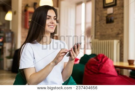 Beautiful Student Girl Using Smartphone For Text Messages In Modern Stylish Coworking Office