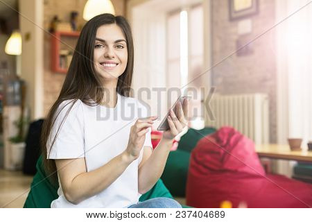 Brunette Girl Using Smartphone For Text Messages In Modern Stylish Coworking Office