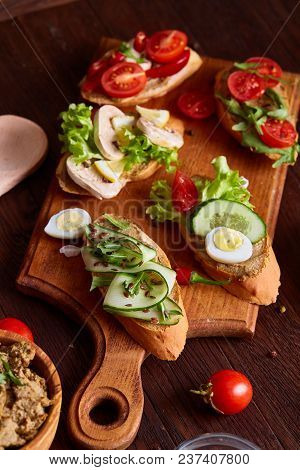 Breakfast Sandwich With Homemade Paste, Vegetables And Fresh Greenson Wooden Cutting Board Over Rust