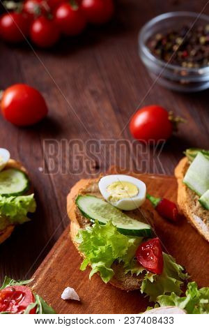 Breakfast Sandwich With Homemade Paste, Vegetables And Fresh Greenson Wooden Cutting Board Over Rust