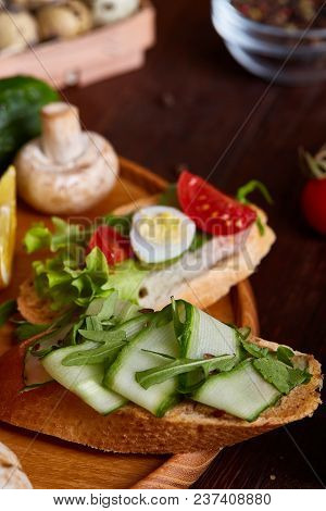 Breakfast Sandwich With Homemade Paste, Vegetables And Fresh Greenson Wooden Cutting Board Over Rust
