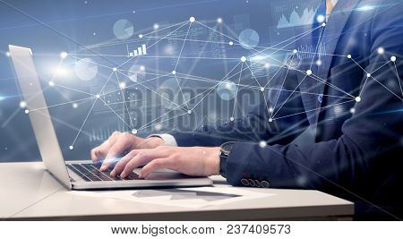 Businessman typing on laptop with linked reports charts grapghs around