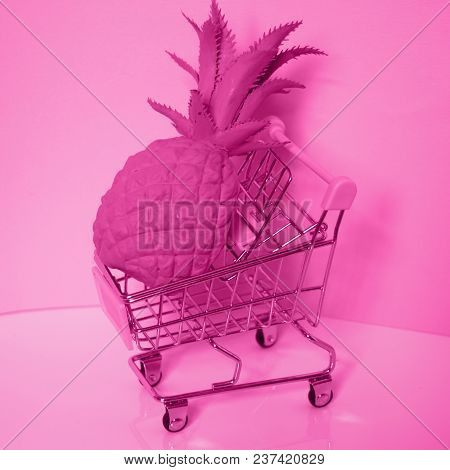 Shopping Cart. Supermarket Trolley With Big Pineapple. Monochrome Pink Colored Photo. Consumerism Co