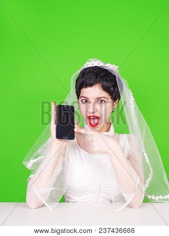 Caucasian Fiancee Holding A Mobile Phone And Pointing At It. Young Fiancee With A Mobile Phone. Fian