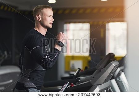 Young Handsome Man With Fitness Tracker In Sport Club. Cardio Workout, Running On Treadmill. Healthy