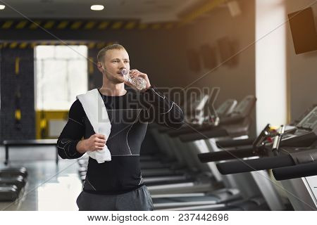 Athletic Young Man Having Rest After Running Training, Drinking Water At Gym, Standing At Treadmill,