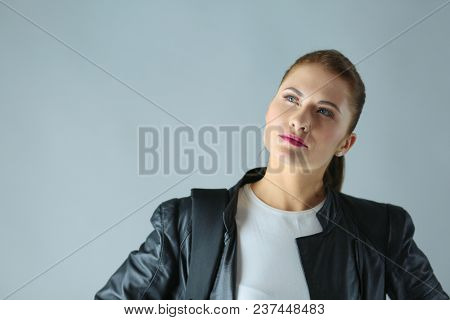portrait of beautiful young brunette woman in stylish black jacket on gray.