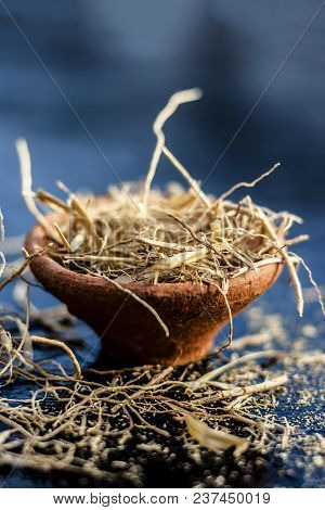 Dried Vetiver Grass Or Khus Or Chrysopogon Zizanioides Grass In A Clay Bowl On Wooden Surface.
