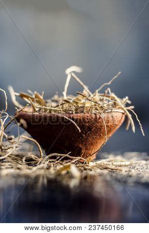 Dried Vetiver Grass Or Khus Or Chrysopogon Zizanioides Grass In A Clay Bowl On Wooden Surface.