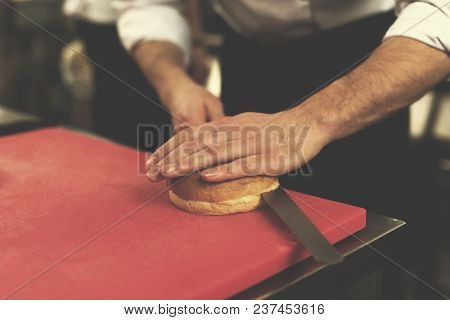 master chef hands cutting rolls for a burger in the rastaurant kitchen