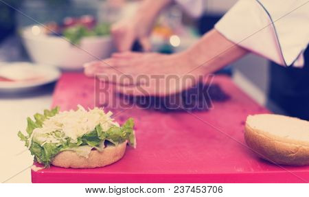 master chef hands cutting salad for a burger in the rastaurant kitchen