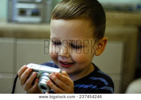 A Small Boy Holds A Camera In His Hands And Smiles, Looks At The Screen. Memories, Photography, Vide