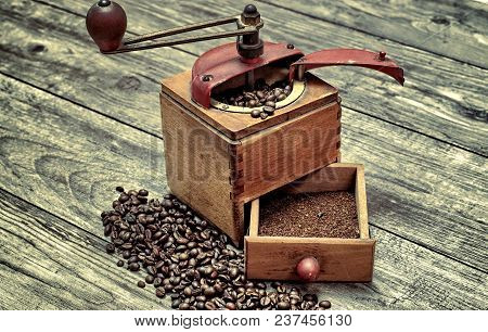 Old Coffee Grinder With Ground Coffee, Coffee Beans On A Wooden Background.