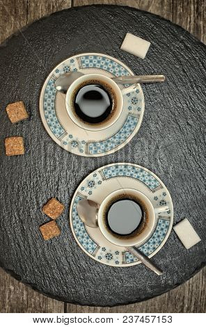 Drinks, Drinking, Energy And Caffeine Concept-two Cups Of Coffee On A Dark Slate Stand And Wooden Ba