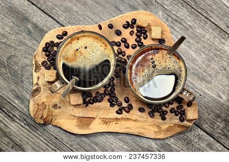 Two Cups Of Coffee,coffee Beans And Brown Lump Sugar On Wooden Background.