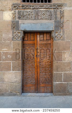 Wooden Ornate Door With Geometrical Engraved Patterns On External Old Decorated Bricks Stone Wall Le