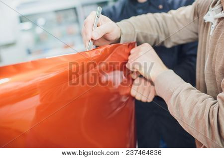 Car Wrapping Specialist Putting Vinyl Foil Or Film On Car. Selective Focus.