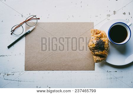 Mockup Blank Craft Sheet Of Blank Craft Paper, Pen, Eye Glasses And Morning Coffee Cup With Croissan