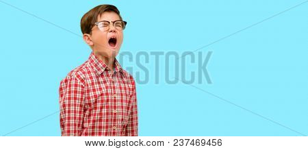 Handsome toddler child with green eyes stressful, terrified in panic, shouting exasperated and frustrated. Unpleasant gesture. Annoying work drives me crazy over blue background