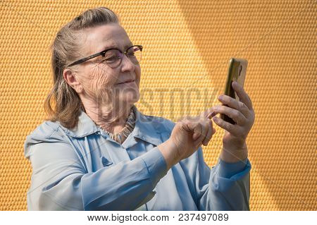 Portrait Of Old Lady, Grandmother Makes Selfie Outdoors At Sun Day. Modern Caucasian Granny Finger  